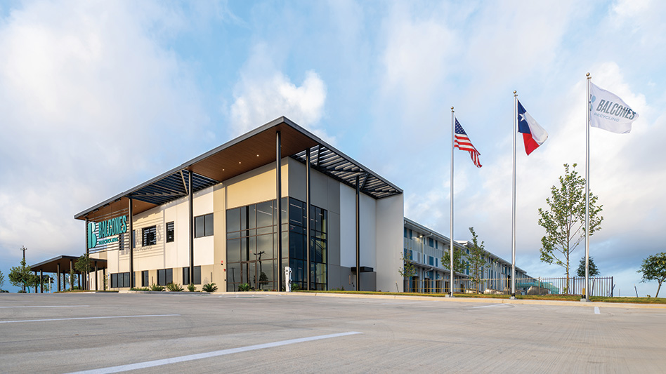 Exterior of Balcones Recycling Facility building with a parking lot and three flag poles.