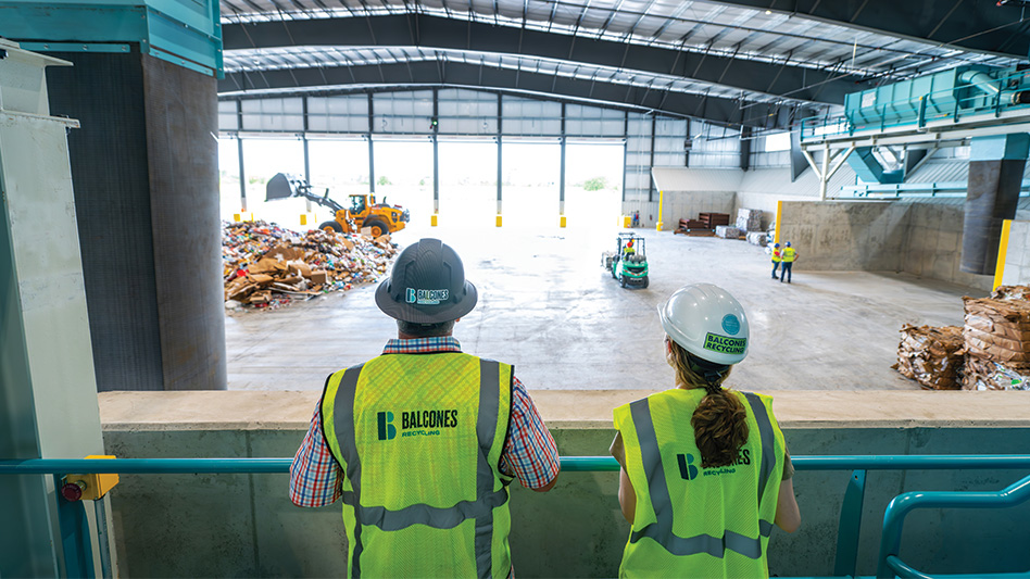 Two Recycling workers looking over a railing at the MRF tip floor.