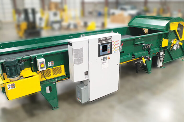 A green optical sorting system with a white control unit labeled "MetalMiner." The control unit has a digital display screen and various buttons and stickers. The background is blurred, indicating an industrial setting.