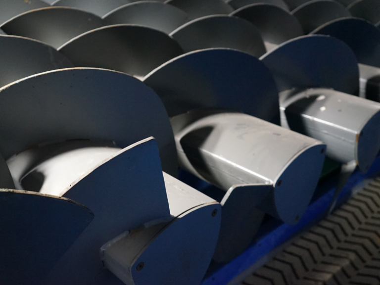 This image shows a series of large, industrial blue-grey metal auger segments with a helical blade pattern, possibly for material handling or conveyance.