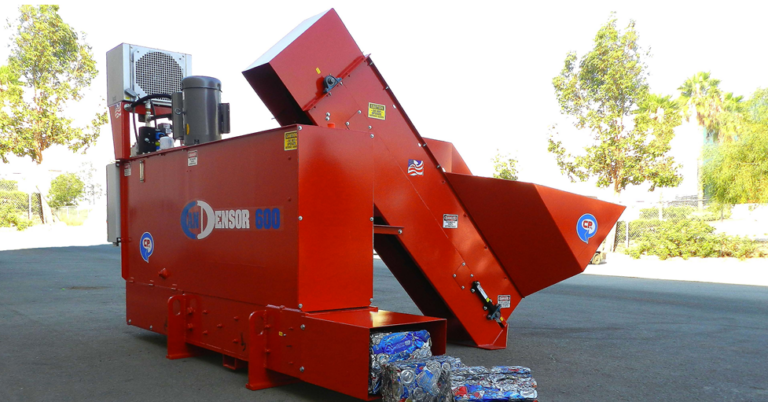 A large, red Can Densifier machine, labeled "CANDENSOR 600" is outdoors. It features a wide conveyor belt and appears to be processing and compacting bottles into bales. There are trees and a clear sky in the background.