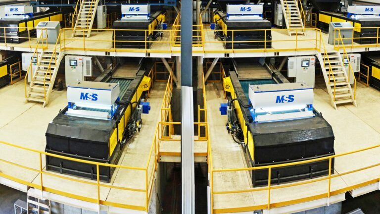 A large, MRF facility showcasing two symmetrical L-VIS sorting machines labeled "MSS". The machines are placed on elevated platforms surrounded by yellow railings and stairs, with additional machinery and equipment visible in the background.