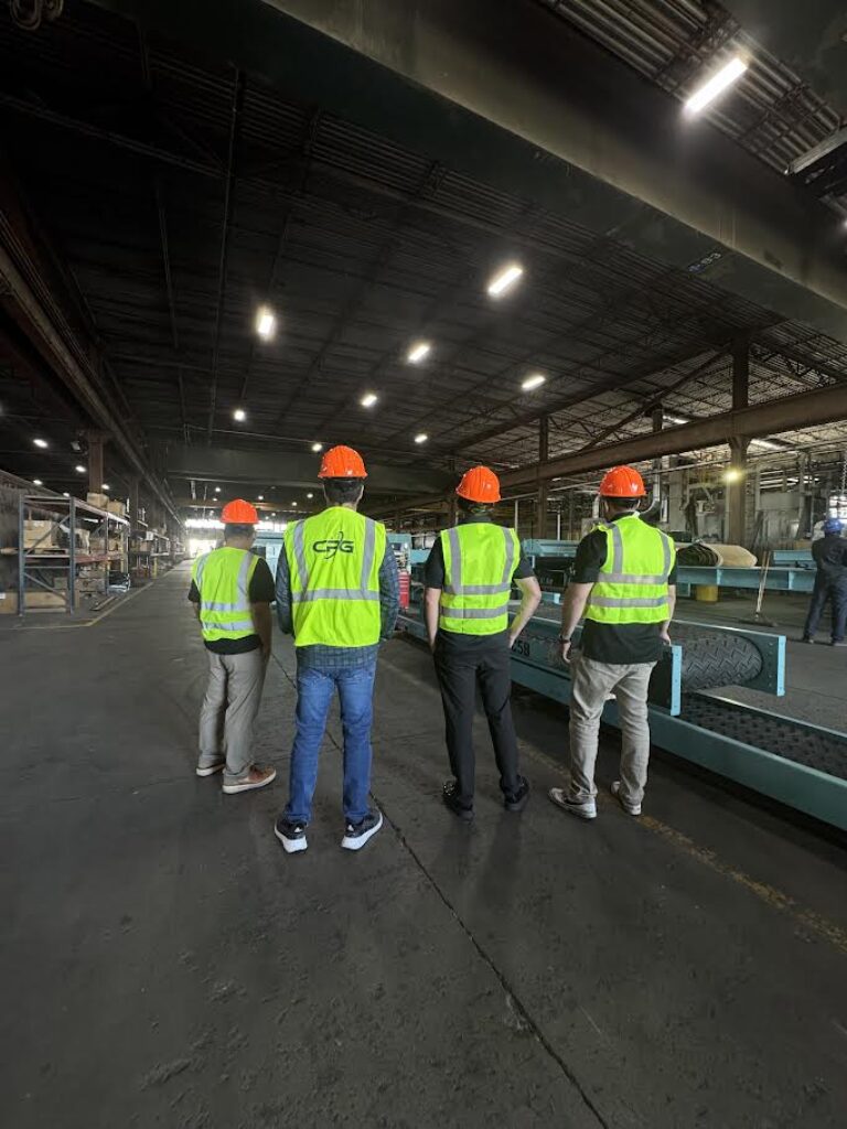 Four men in safety gear standing in a recycling manufacturing warehouse